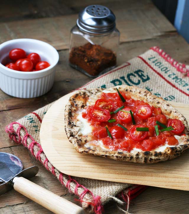 意式皮塔披萨。大蒜，新鲜的马苏里拉奶酪和西红柿。点击查看食谱!